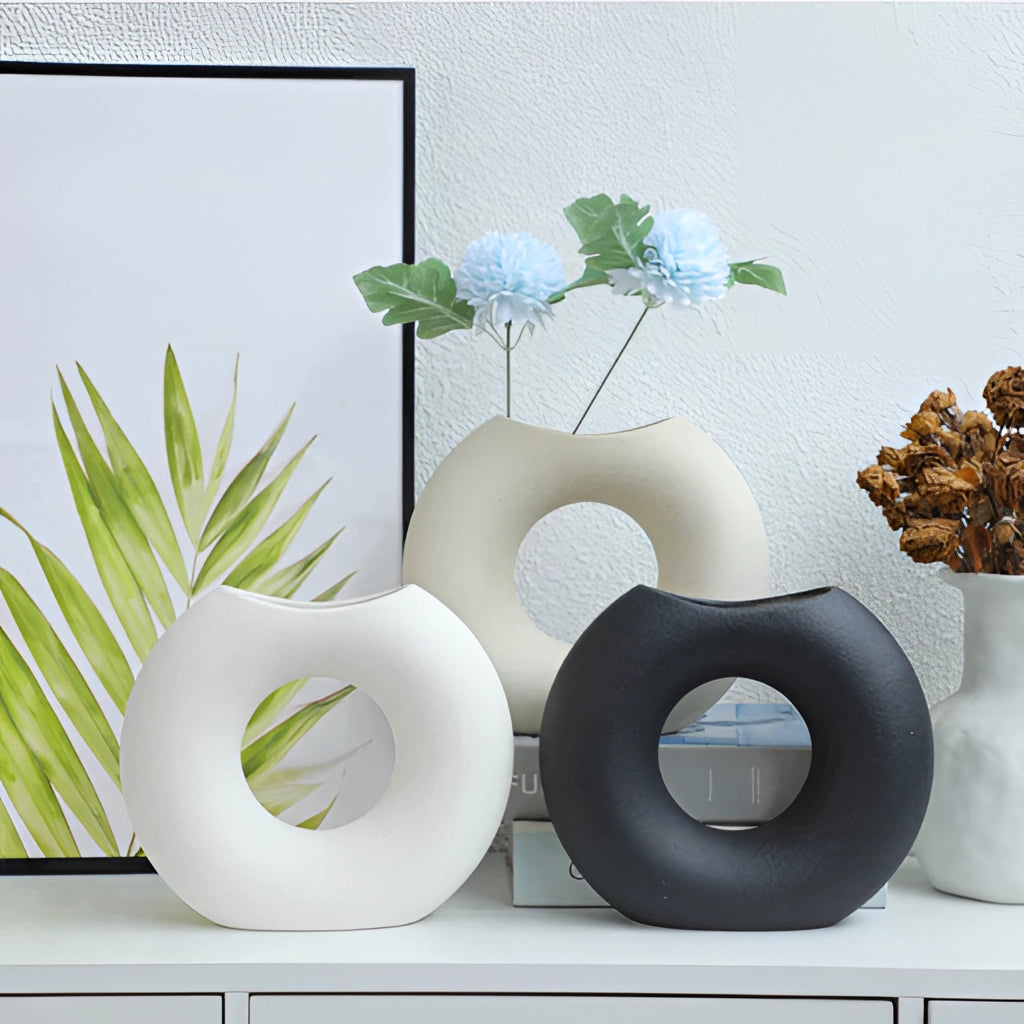 Nordic Style Ceramic Donut Vase in modern circular design, displayed in a stylish living room setting with a small plant beside it.