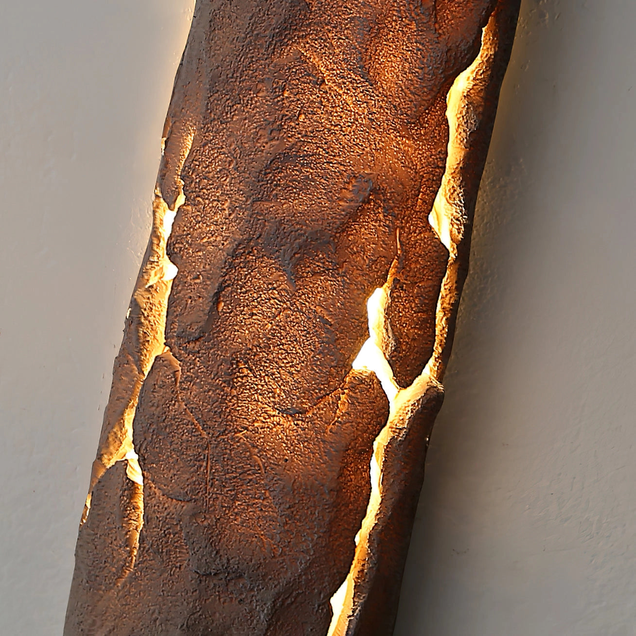 Outdoor wall light with IP65 waterproof rating, featuring a premium resin faux rock finish in amber tones, mounted on a wooden surface.