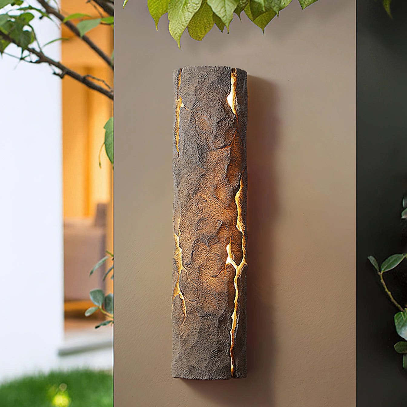 Outdoor wall light with IP65 waterproof rating, featuring a premium resin faux rock finish, surrounded by green leaves and branches.
