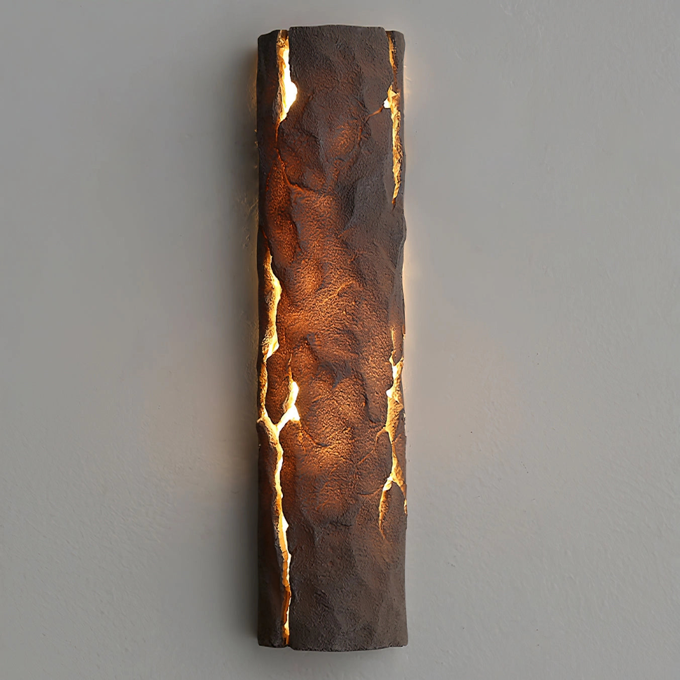 Outdoor wall light with IP65 waterproof rating, featuring a premium resin faux rock finish in amber and gold tones, rectangular shape, mounted on wood and metal background.