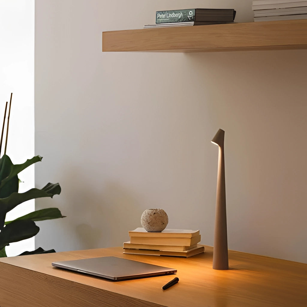 Portable rechargeable LED table lamp with aluminum construction, placed on a wooden surface, showcasing three light intensities, surrounded by houseplants and interior decor elements.