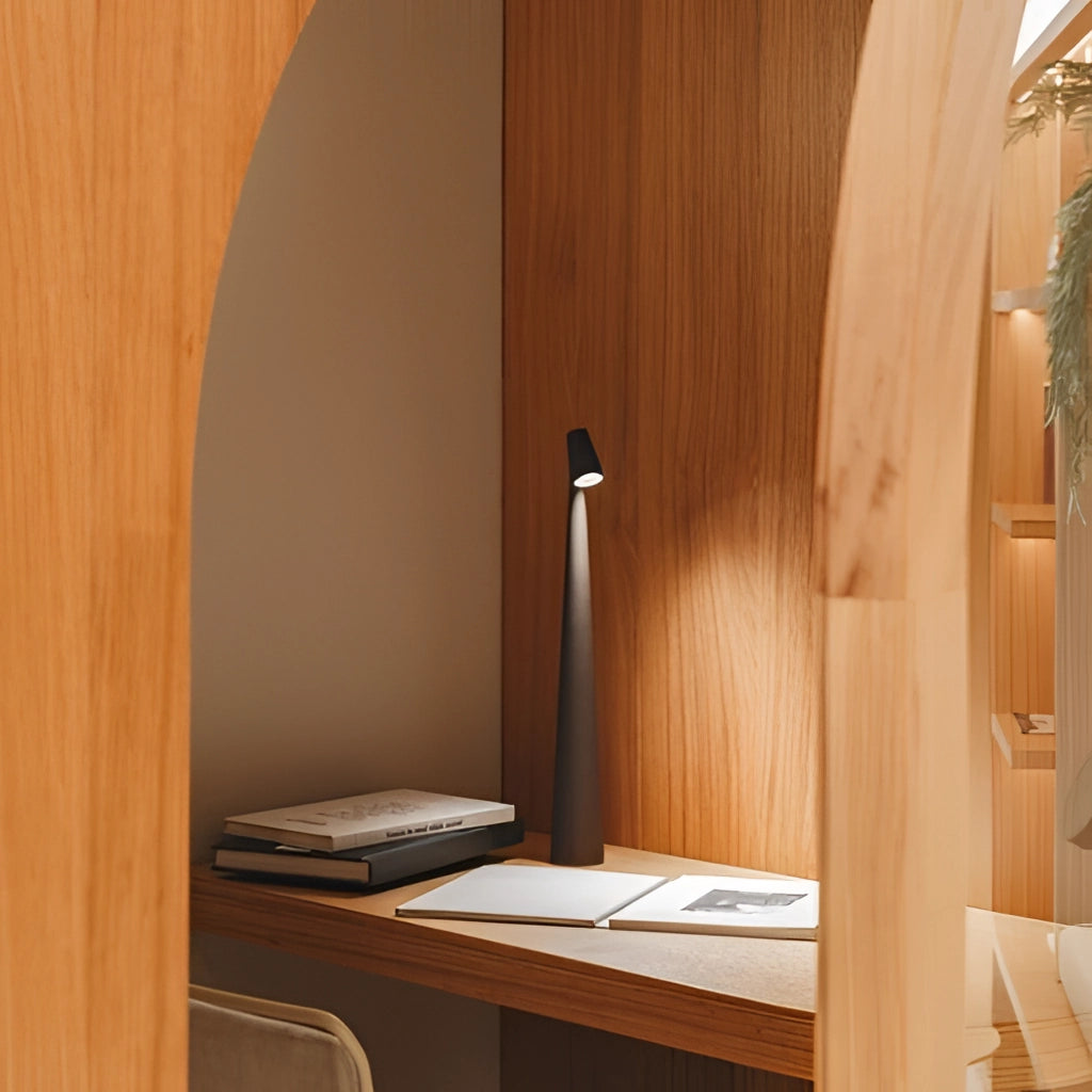 Portable rechargeable LED table lamp with aluminum construction on a wooden table, featuring three light intensities, surrounded by houseplants in a well-designed interior.