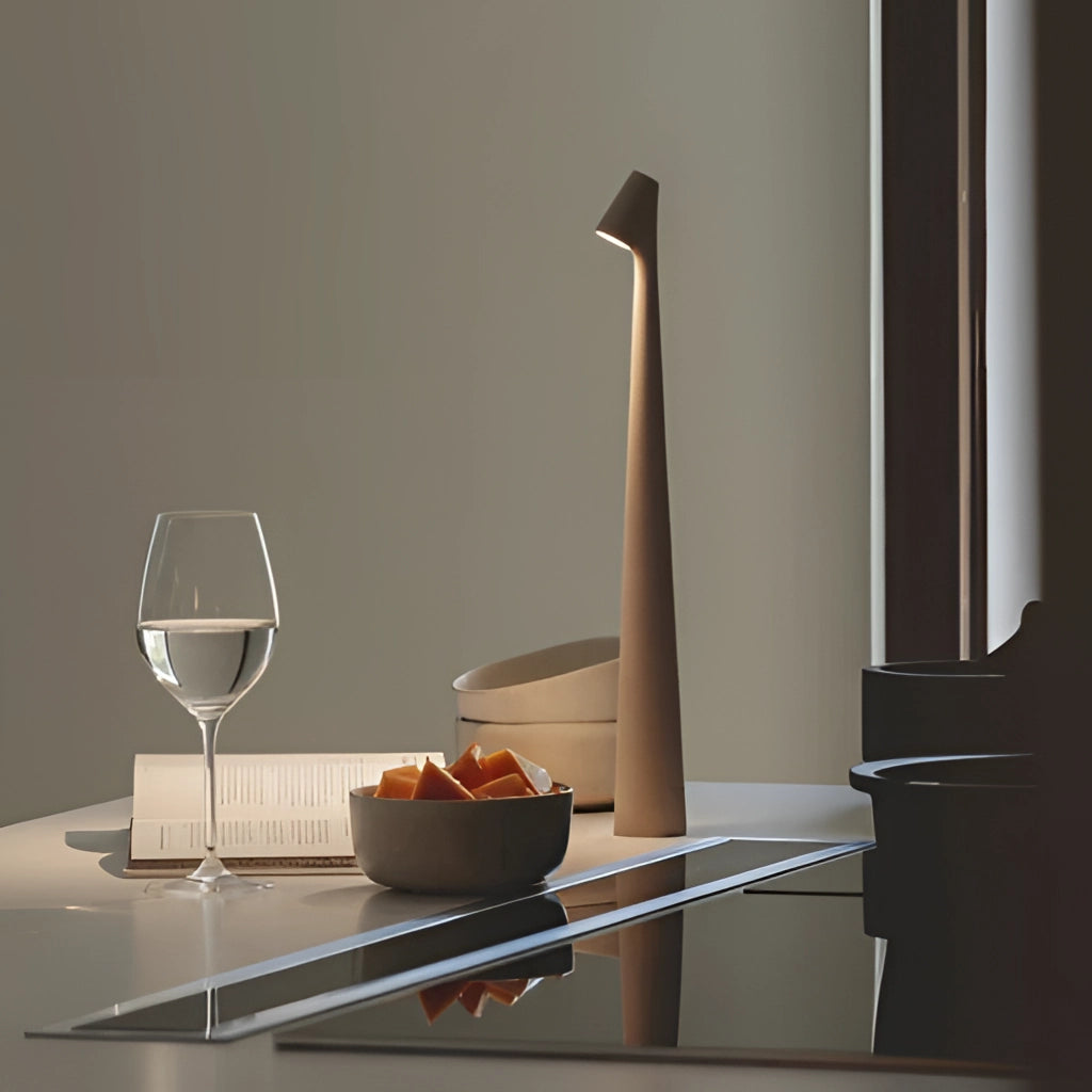 Portable rechargeable LED table lamp with aluminum construction on a wooden table with tableware and dishware in the background.