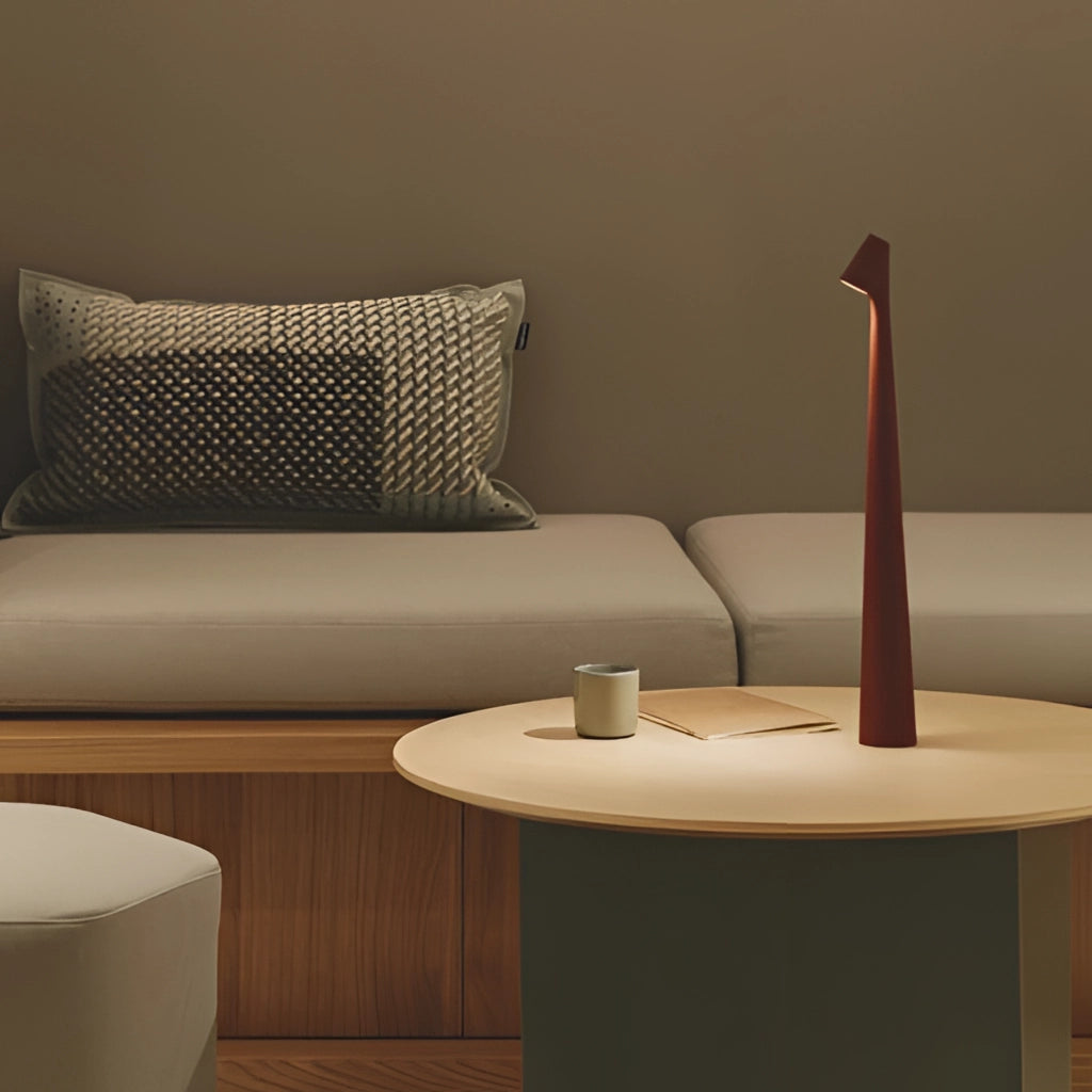 Portable rechargeable LED table lamp with aluminum construction and adjustable light intensities, placed on a wooden table in a comfortable living room setting.