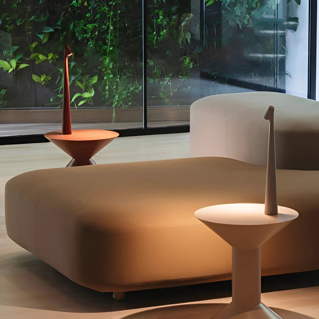 Portable rechargeable LED table lamp with aluminum construction on a wooden table, next to a small potted plant, showcasing a modern interior design.