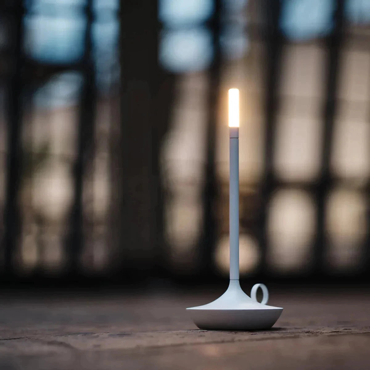 A white Nordic candlestick light with adjustable dimming and rechargeable features, made from aluminum casing, showcased in a dark, minimalistic setting.
