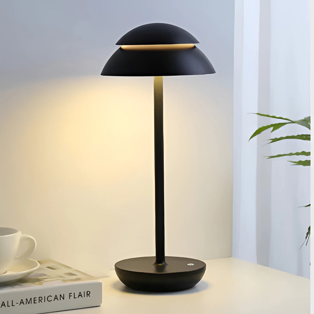 A black Scandinavian design table lamp on a white surface with a small plant and a white coffee cup nearby.