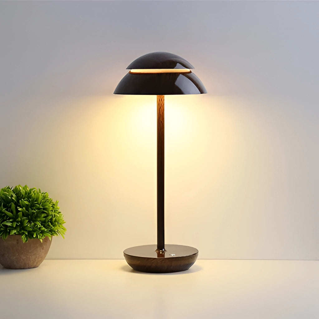 A Scandinavian design table lamp with a walnut base, featuring a sleek white lampshade, placed next to a potted plant.