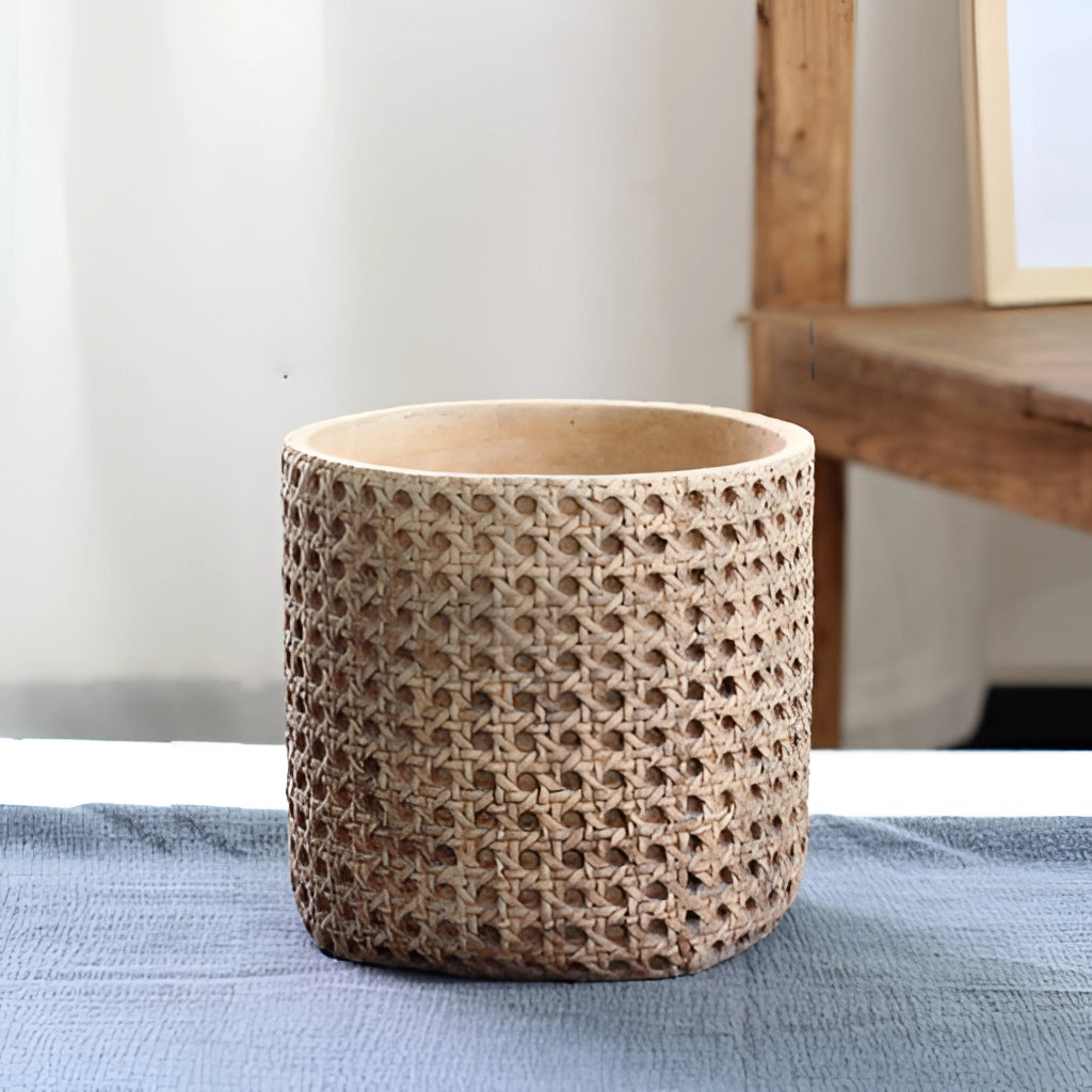 Large rattan cement planter with natural texture, placed on a wooden surface.