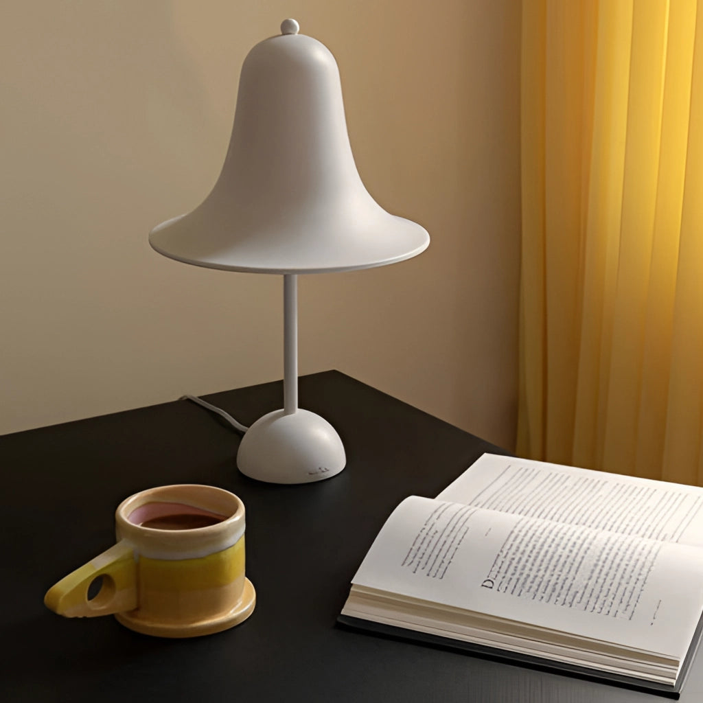 Rechargeable LED lamp with touch sensor emitting light on a wooden table next to a white coffee cup.