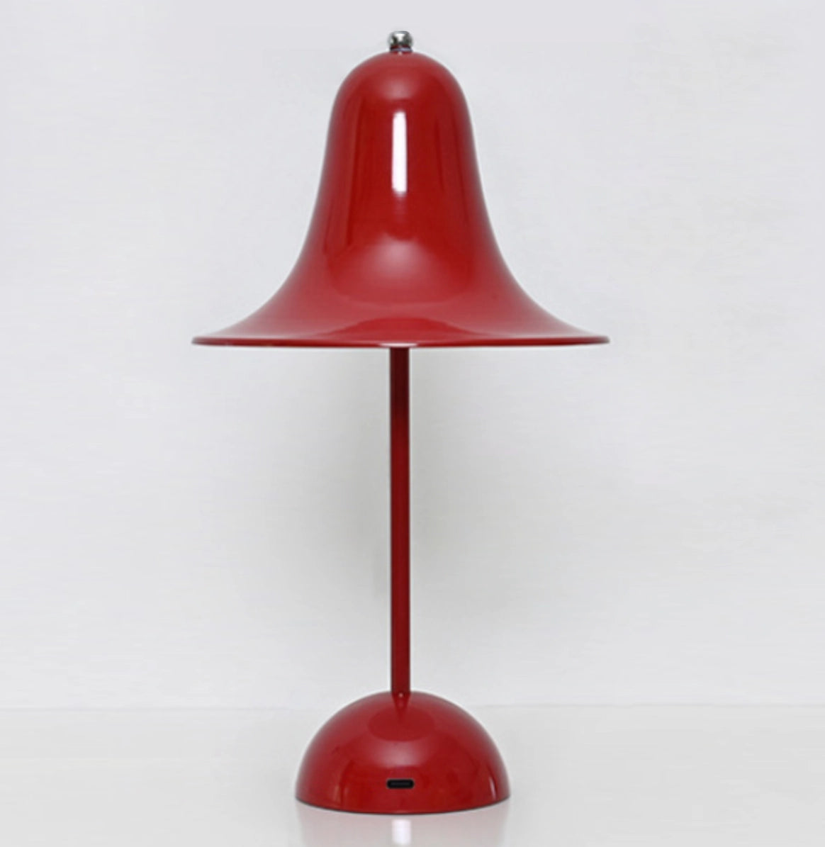 Rechargeable red LED lamp with touch sensor, placed next to a plant, featuring a metal lampshade.