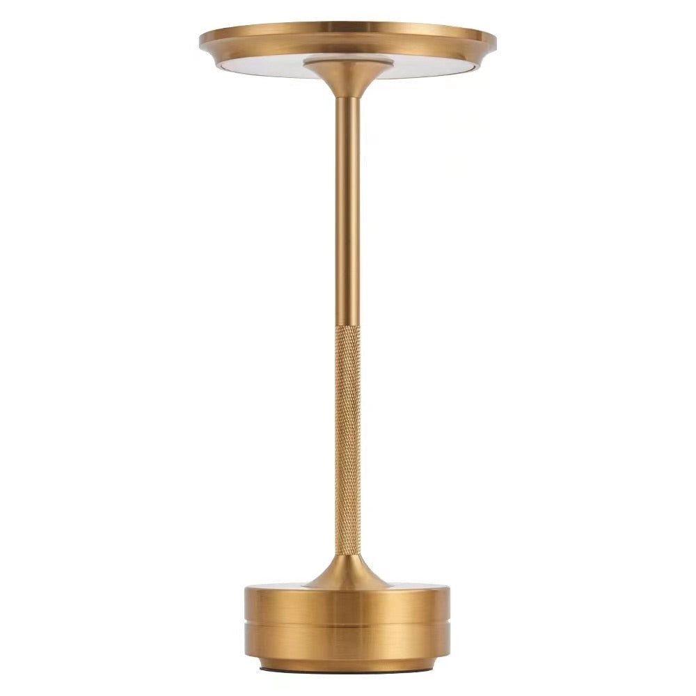 Rechargeable LED table lamp with a gold finish, featuring a cordless design and mood lighting, placed on a wooden surface.