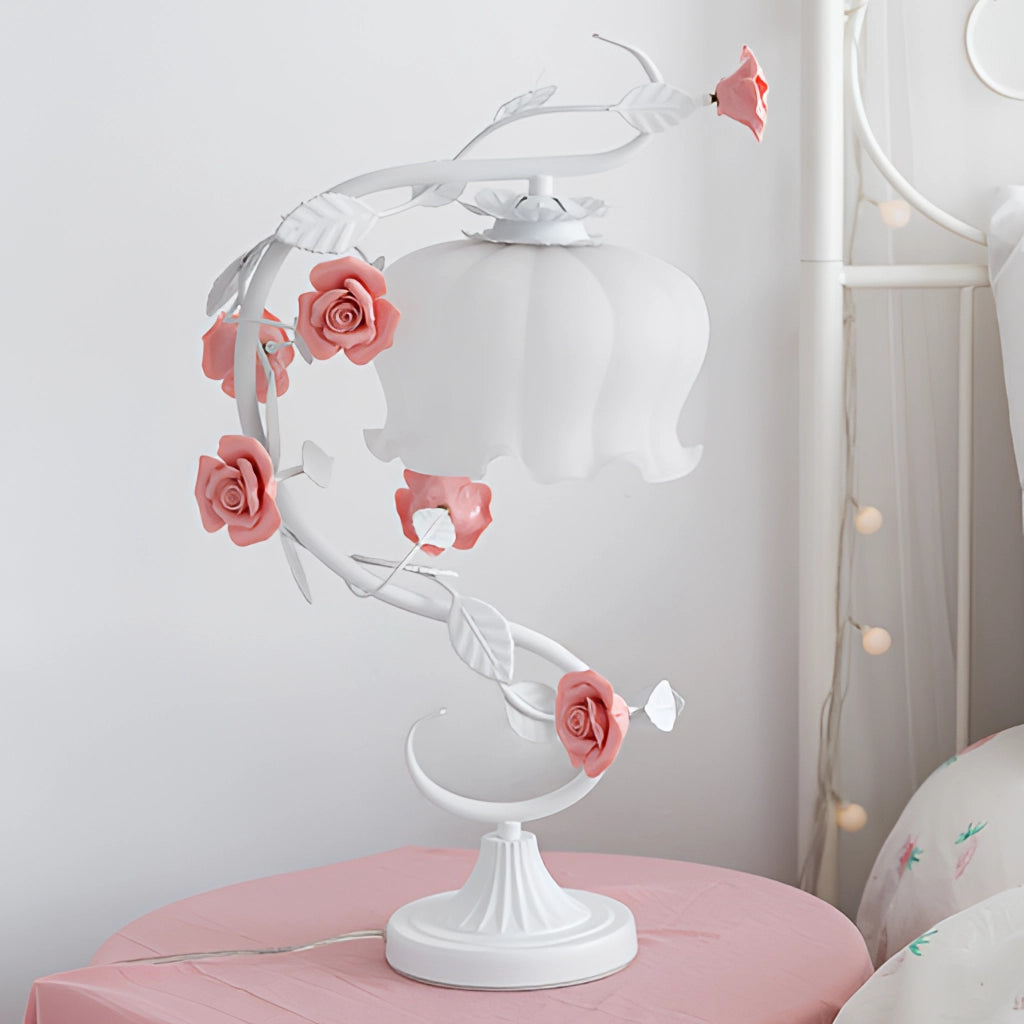 Elegant white table lamp with artificial pink rose encased, placed on a desk.