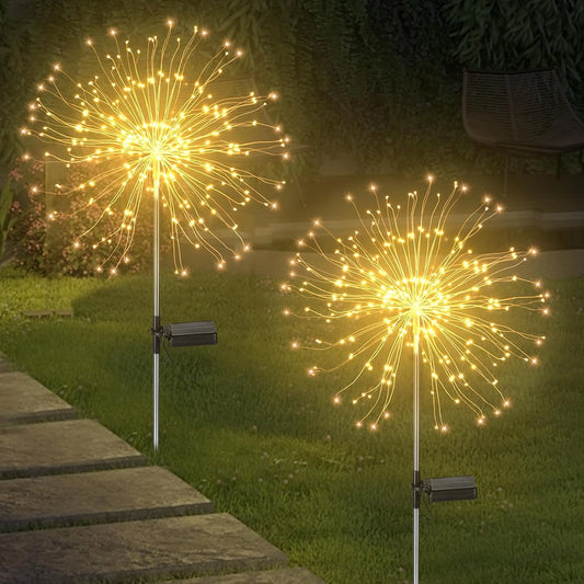 Pack of 2 Solar Firework LED String Lights in Warm White, displayed outdoors in a yard setting with trees and grass, illuminating the area with dual lighting modes.