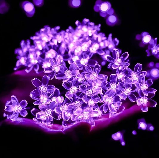 Solar Flower Garden LED Light Strips illuminating with vibrant purple and magenta hues, highlighting flowering plants and petals.
