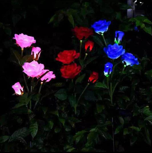 White solar LED rose lights illuminating a garden at night with realistic rose petals and leaves.
