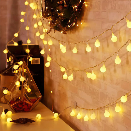 Solar powered waterproof outdoor LED string lights in warm white, 72ft long with 200 LEDs, illuminating a garden with a soft amber glow, perfect for decoration and events.