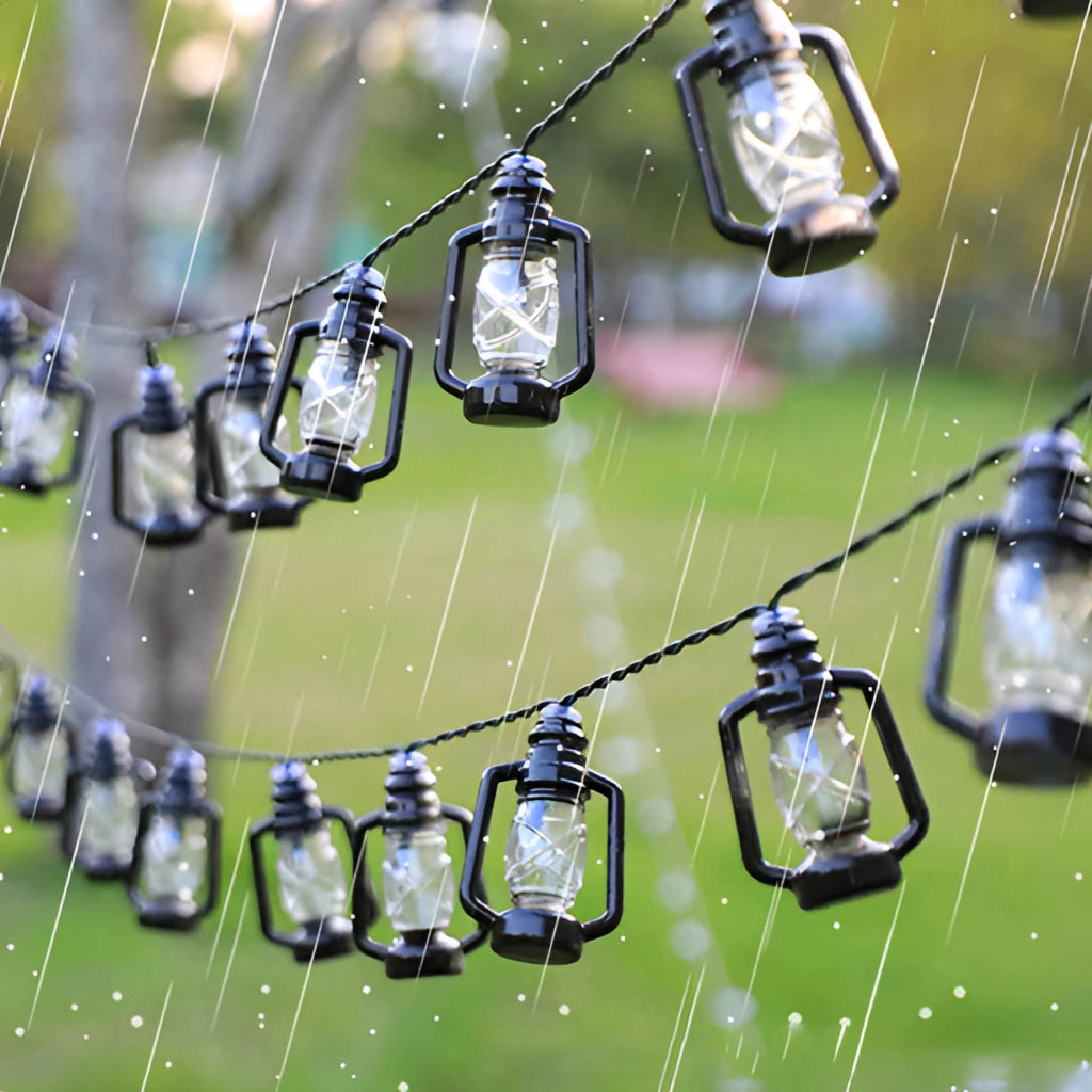 Outdoor garden with solar string lights featuring colorful LED lanterns hanging among green plants and trees.