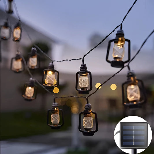 Solar string lights with warm white LED lanterns, 23ft length, featuring 50 lanterns, draped on a wooden structure outdoors with trees and plants in the background.