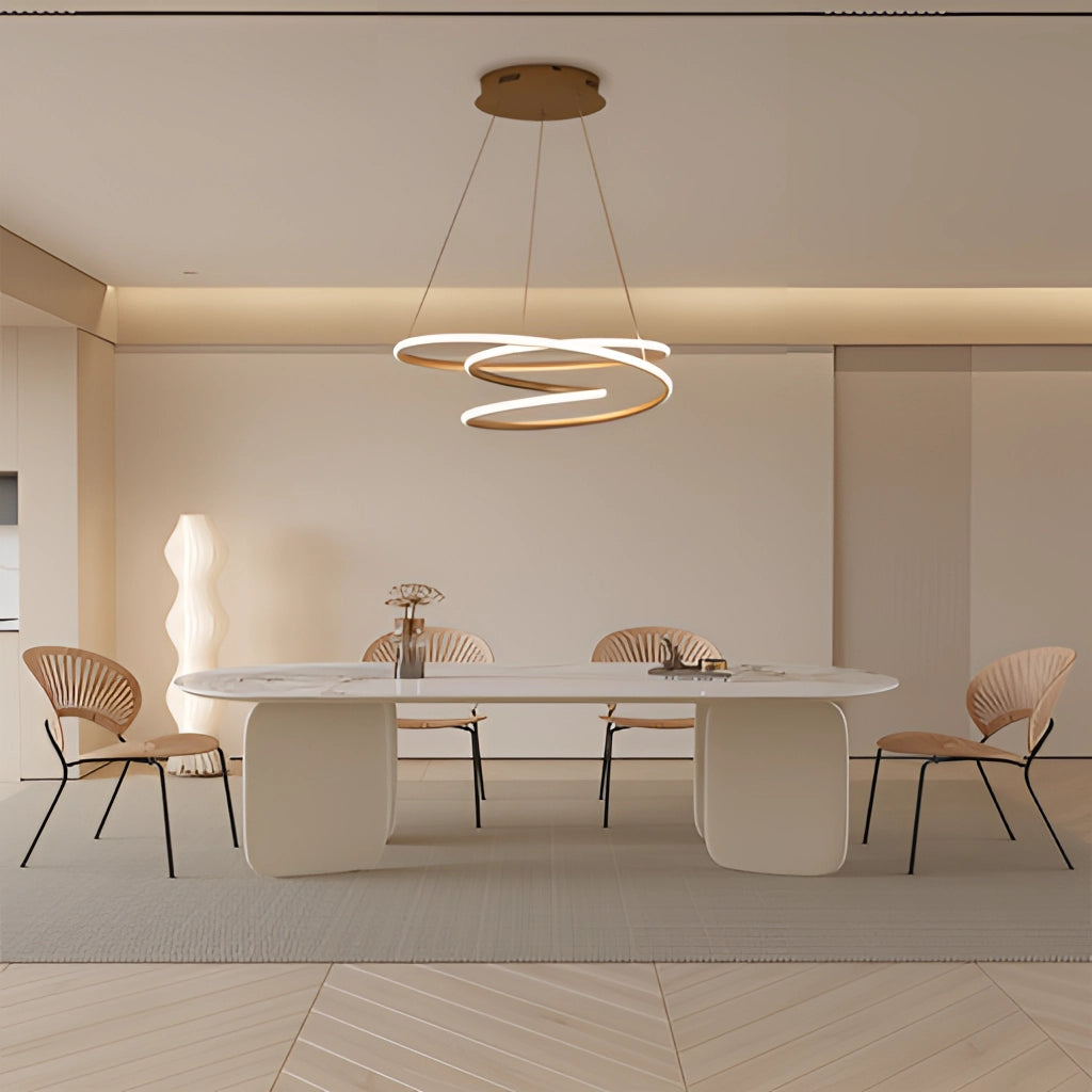 Modern spiral pendant light with warm illumination, hanging over a wooden table and beige chairs in an elegantly designed interior.