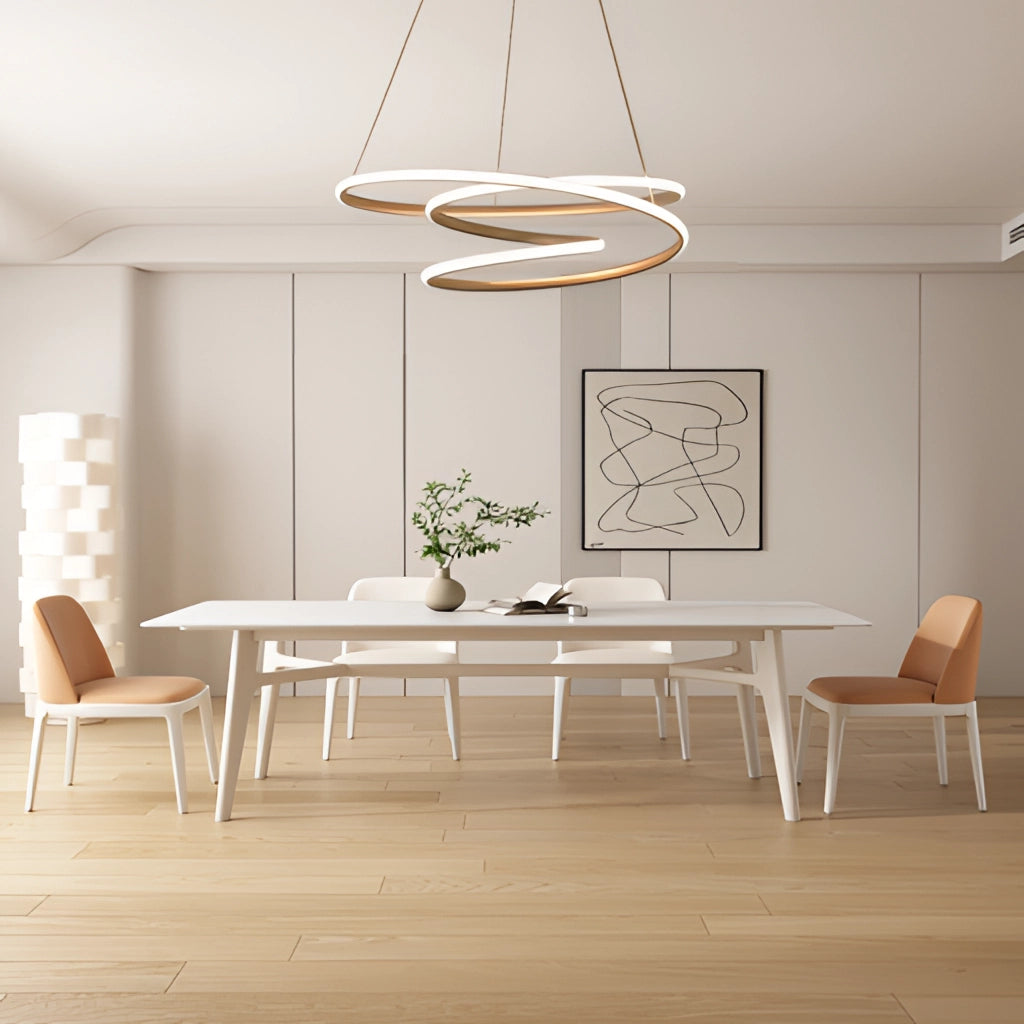 Modern aluminum spiral pendant light with warm illumination, hanging above a wooden table and chairs in a well-designed interior with beige flooring and decorative plants.
