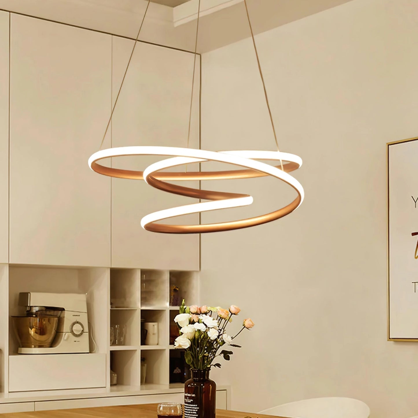 Elegant spiral pendant light with warm illumination hanging above a modern interior space featuring a wooden table with houseplants and a flower vase.