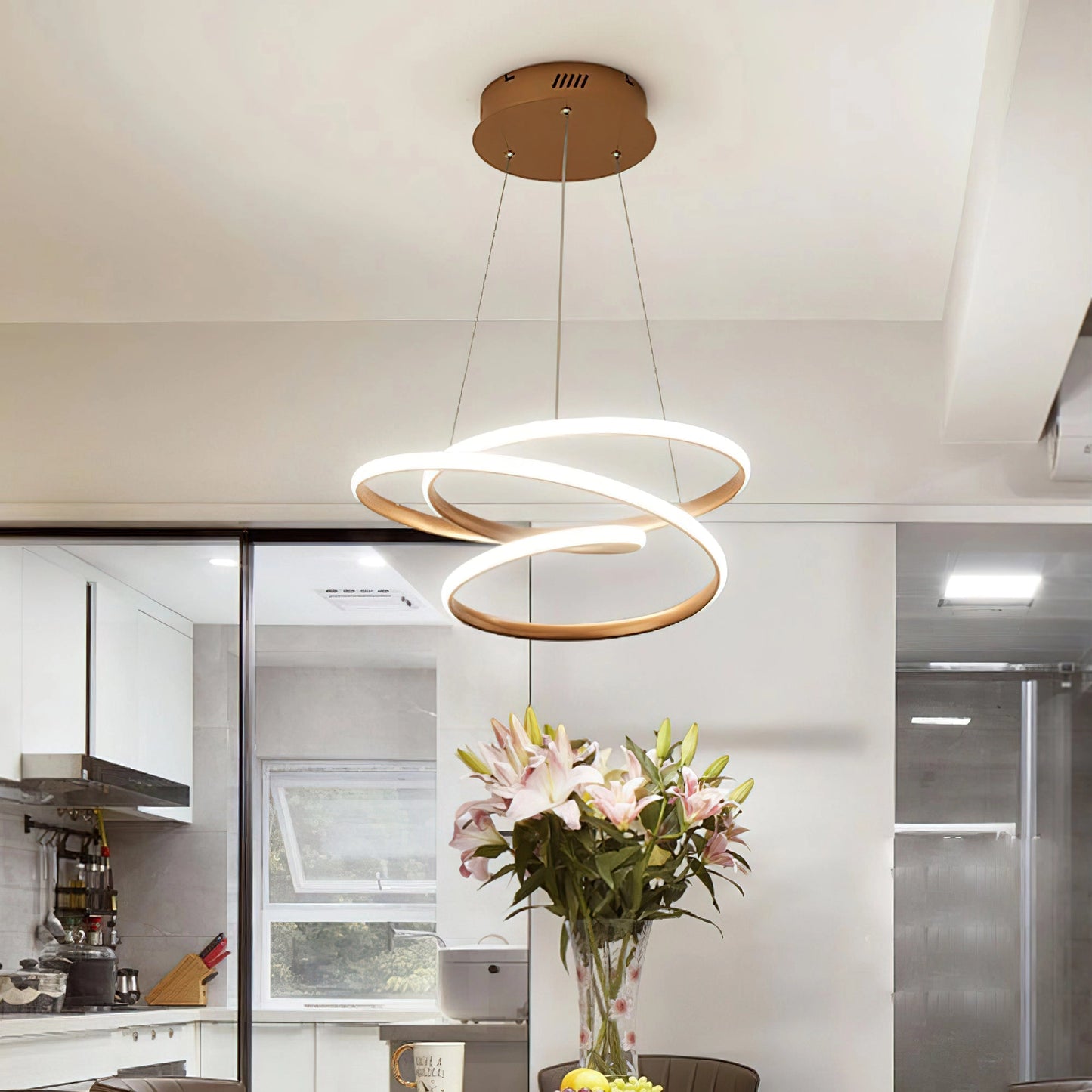 Elegant Spiral Pendant Light providing warm illumination, made of modern aluminum, hanging above a wooden table with a flowerpot and orange vase in a stylish interior design setting.