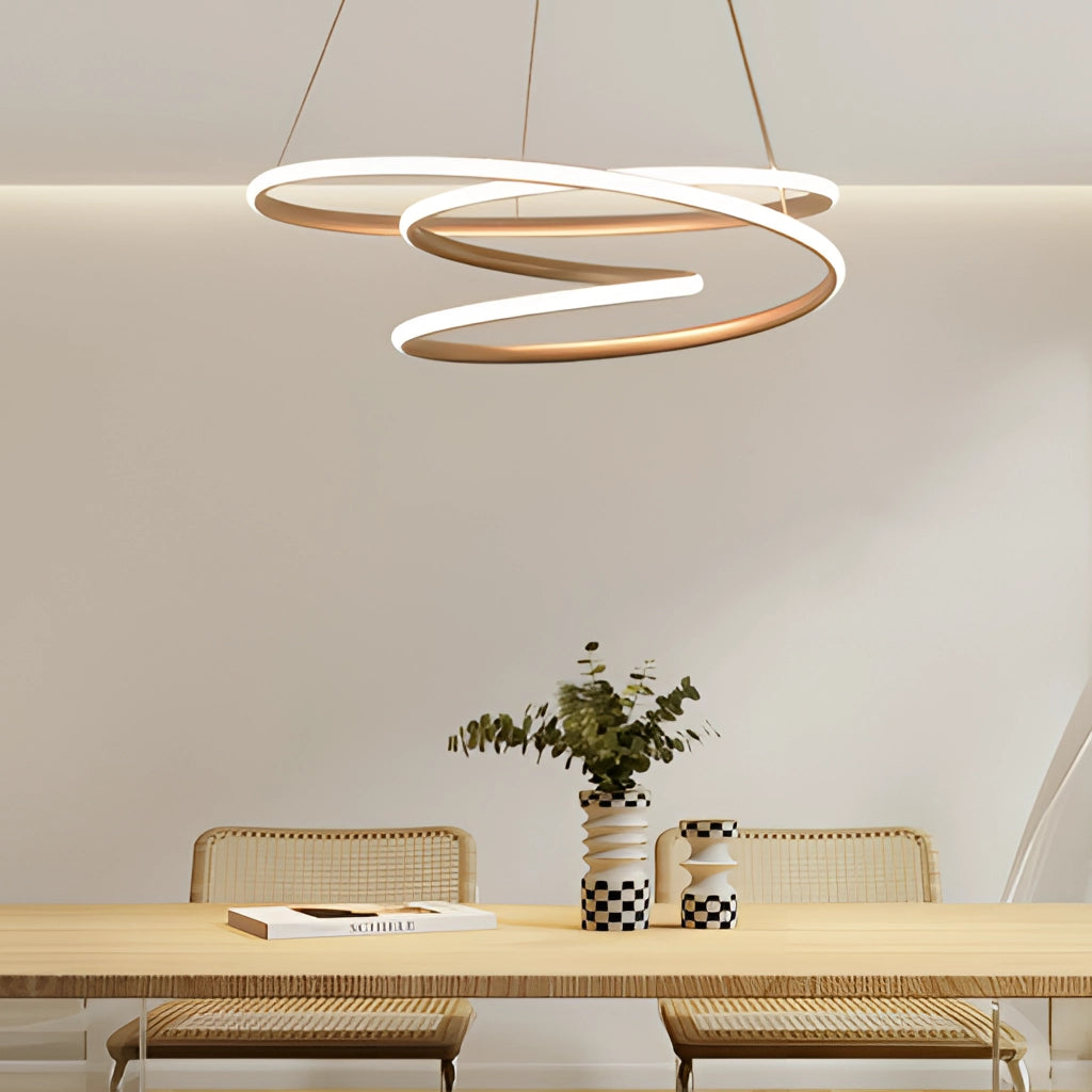 Elegant modern aluminum spiral pendant light providing warm illumination, hanging above a wooden table with houseplants and white decor in a contemporary interior design setting.