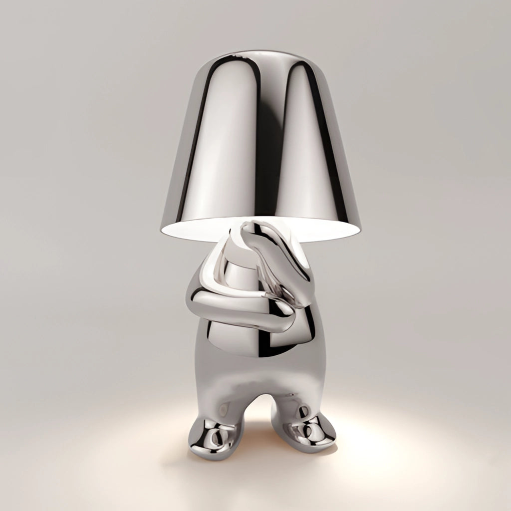 A sleek silver lamp featuring a thoughtful figure in a sitting pose, ideal for desk or nightstand lighting.