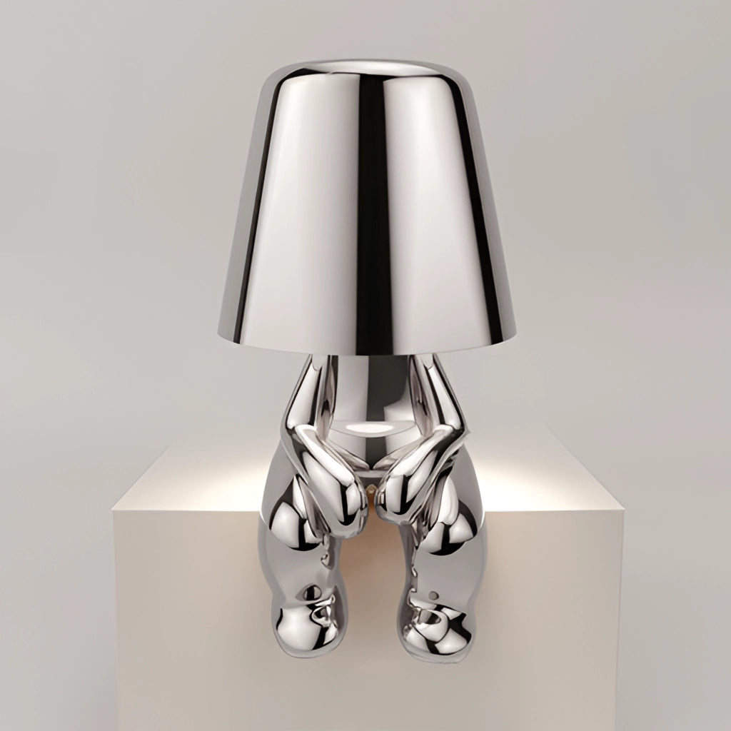 Stylish Thinker Lamp Lars variant in silver placed on a wooden table beside a small plant, featuring a rectangular metal base and a sleek lampshade, perfect for desk and nightstand lighting.