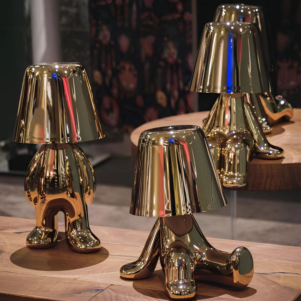 A stylish lamp with a thinker statue base, featuring serene desk and nightstand lighting, accompanied by a glass lampshade and metal accents.