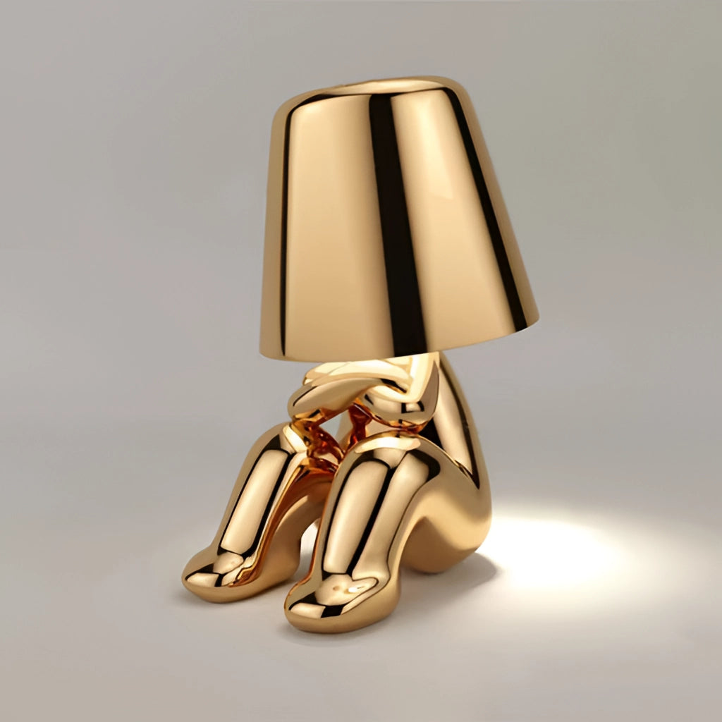 Stylish Thinker Lamp - Serene Desk and Nightstand Lighting in Gold, featuring a wooden base and elegant design, placed beside a potted plant and high heels for a chic aesthetic.