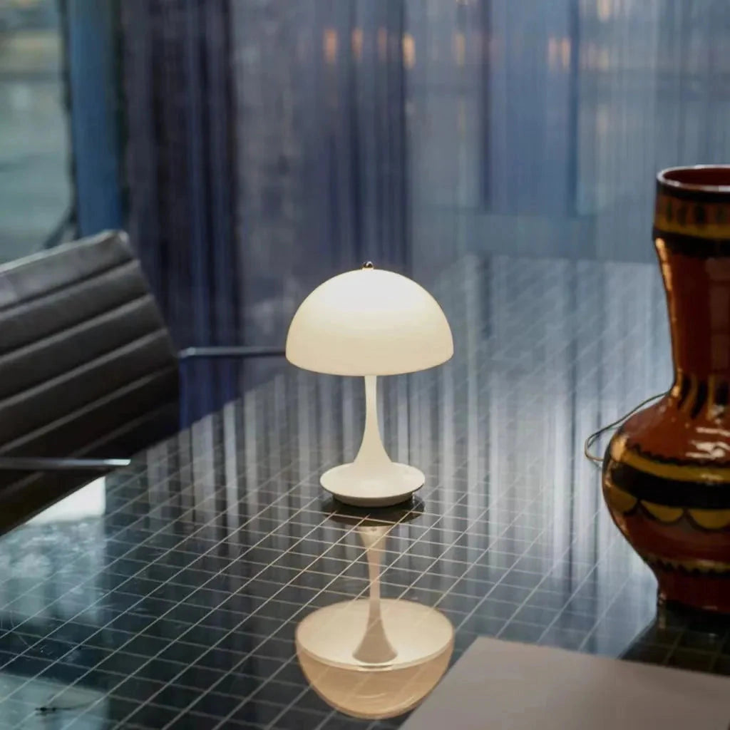 Table Lamp Louis Poulsen Panthella 160 Portable in white, black, orange, gold, and gray set in an interior design scene with wooden flooring and artistic elements.