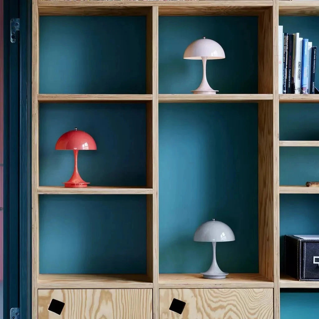 A white Louis Poulsen Panthella 160 portable table lamp placed on a wooden shelf in a stylish interior setting.