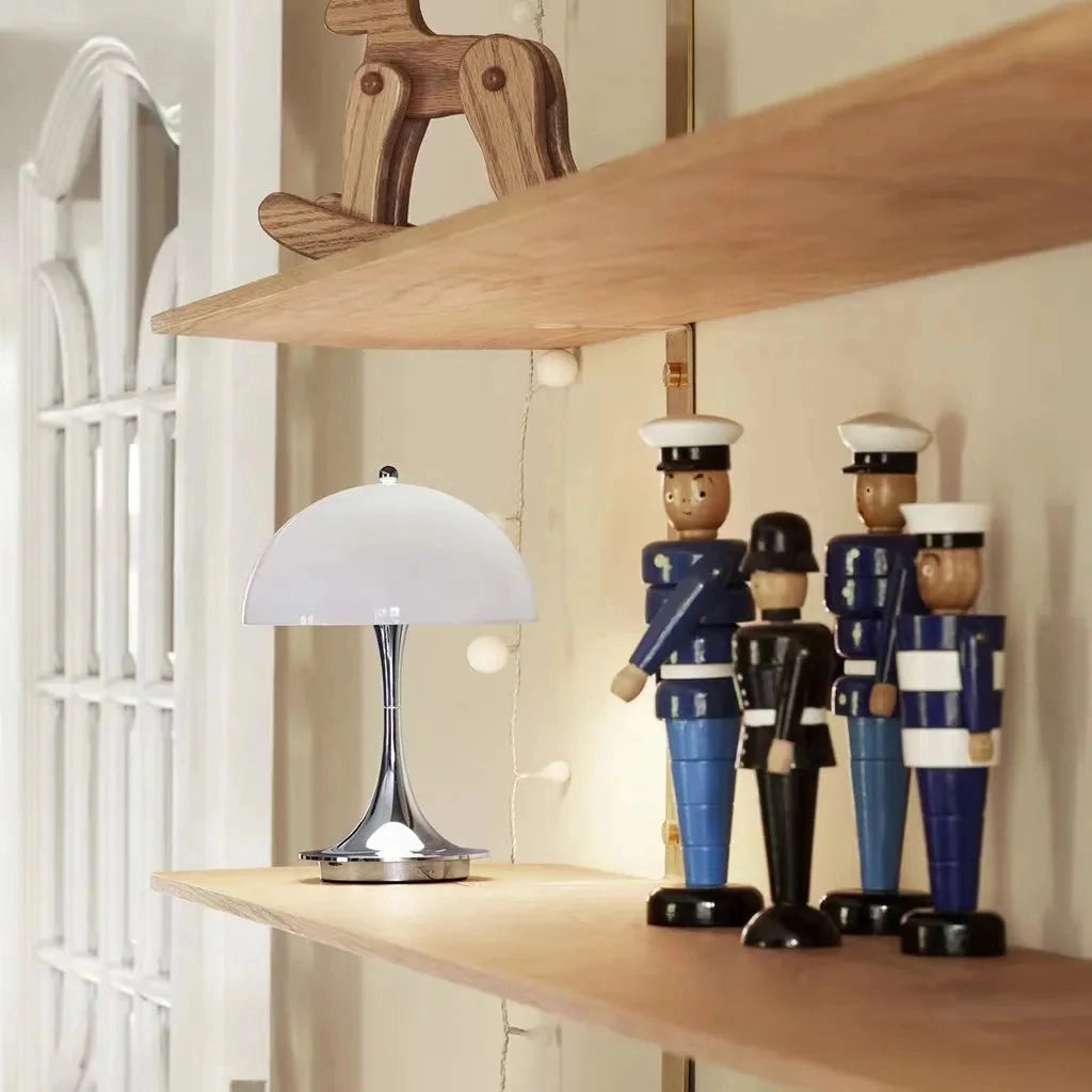Table Lamp Louis Poulsen Panthella 160 Portable in White, Black, Orange, Gold, and Gray displayed on a wooden shelf in a stylishly designed room.