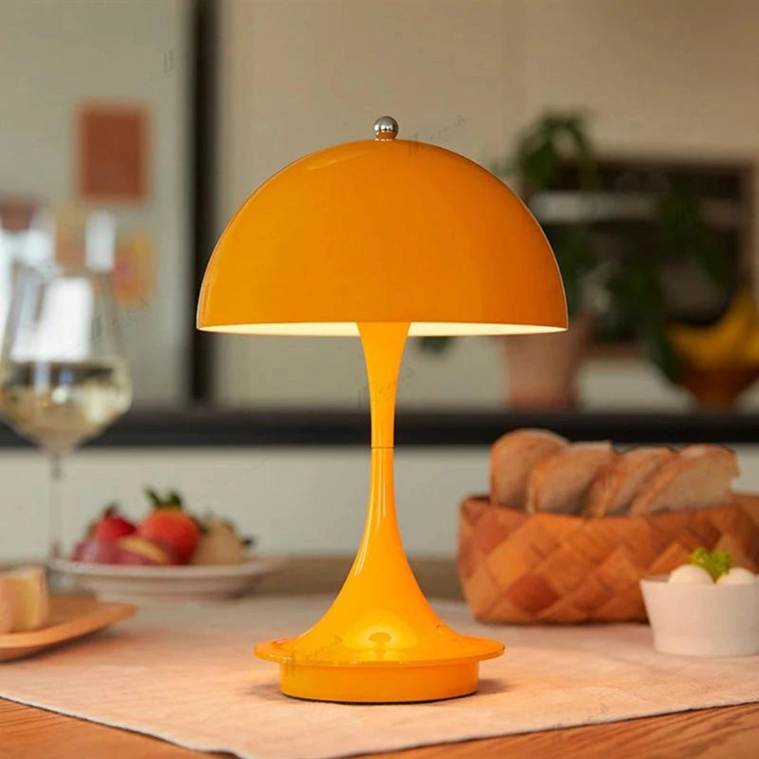 An orange portable Table Lamp Louis Poulsen Panthella 160 on a wooden table.