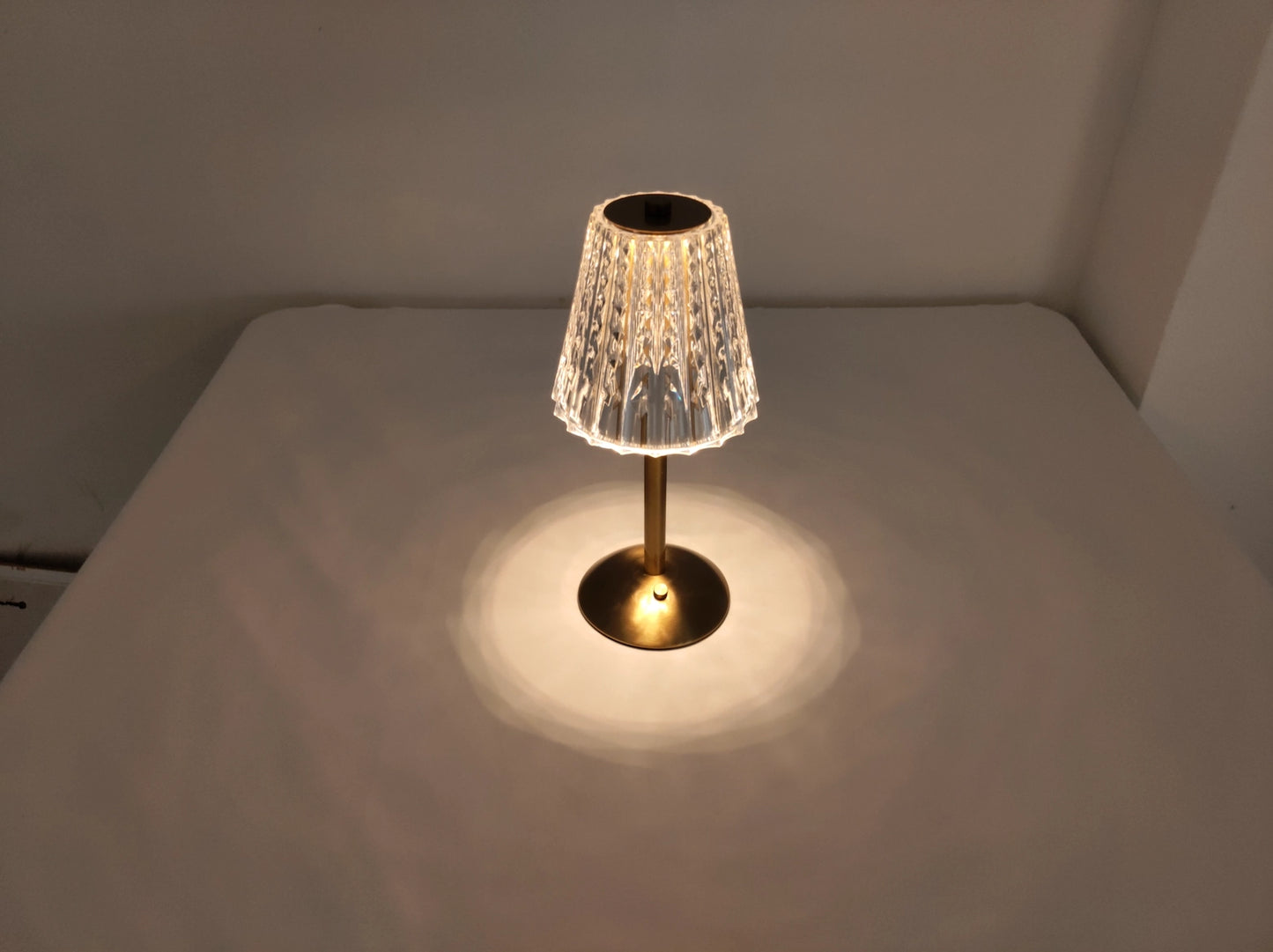Cordless LED table lamp with tricolor dimmable settings on a wooden table with flooring visible in the background.