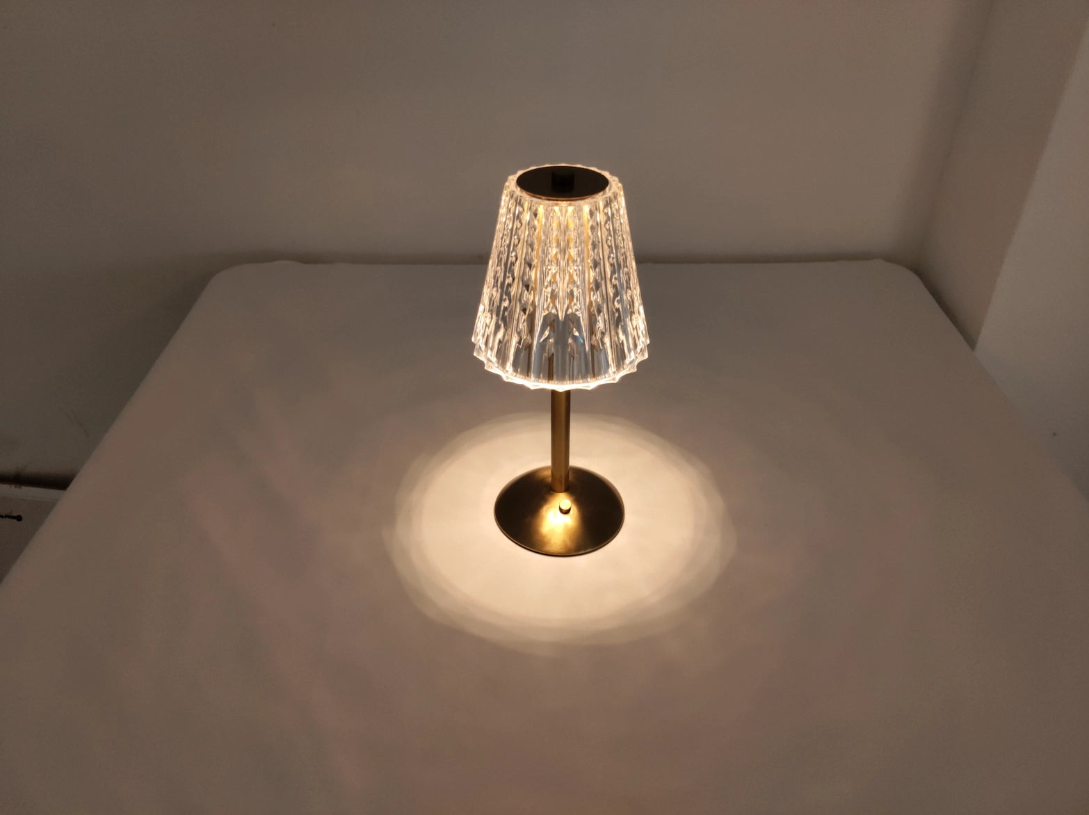 Cordless LED table lamp with tricolor dimmable settings on a wooden table with flooring visible in the background.