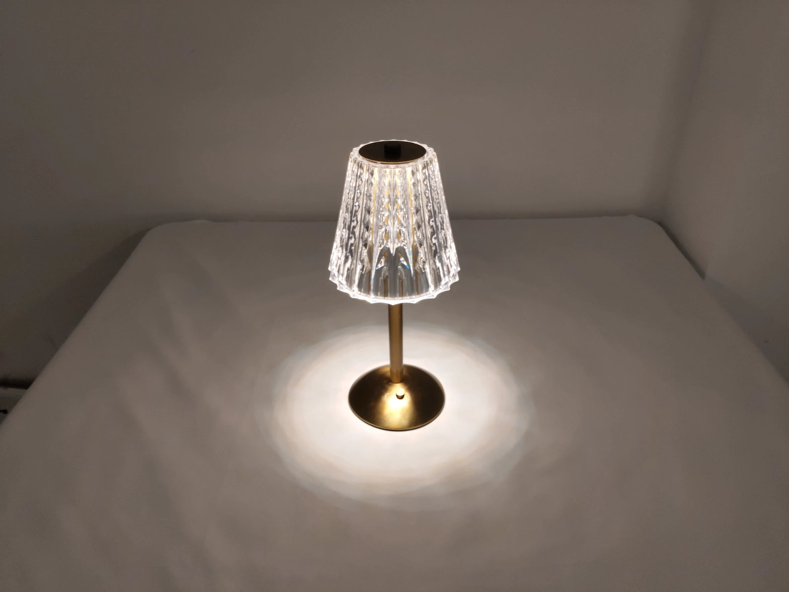 A tricolor dimmable cordless LED table lamp with a wooden base on a hardwood floor.