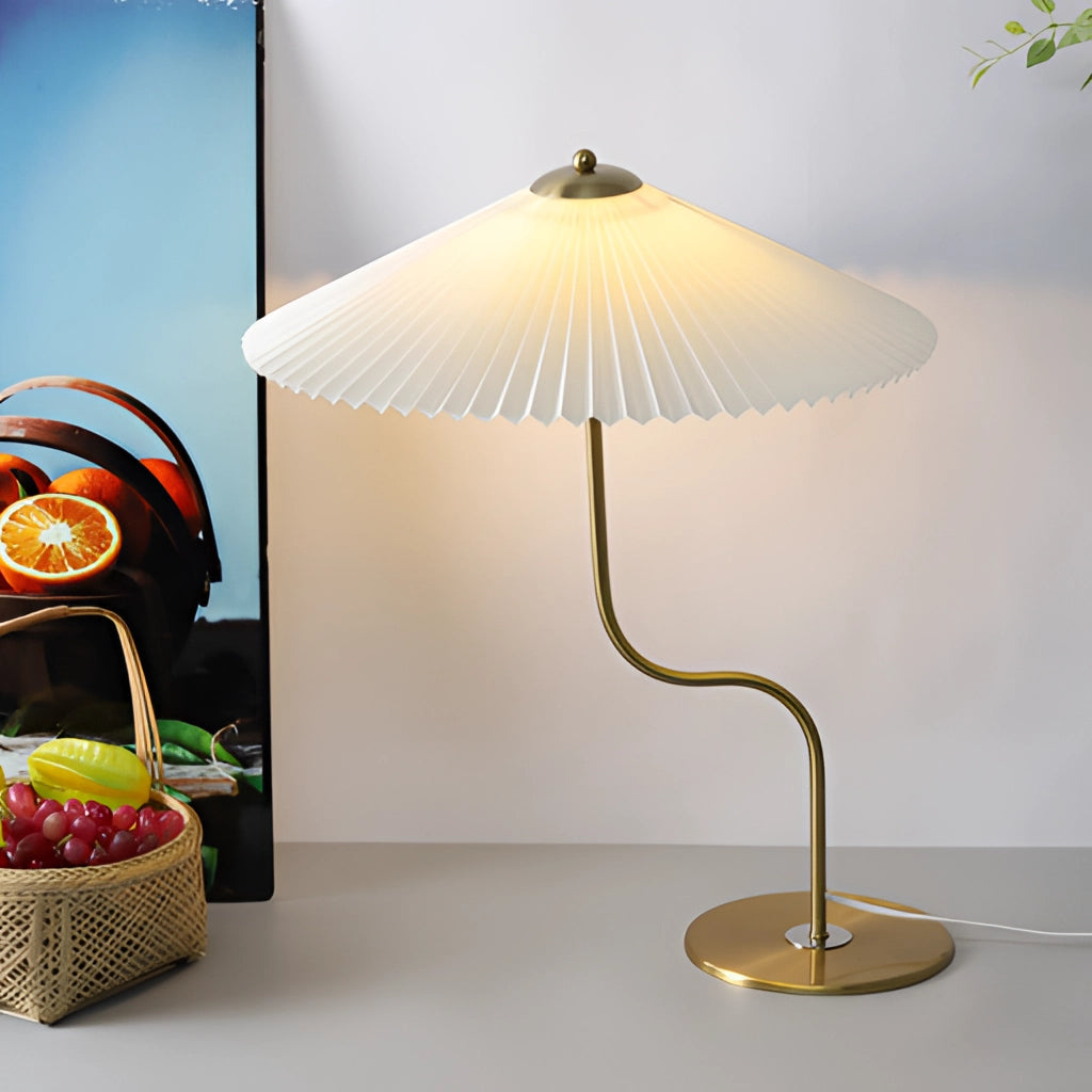 A table lamp with an umbrella-shaped shade featuring a yellow diamond pattern and floral designs, displayed in an interior setting with dark green and khaki accents.