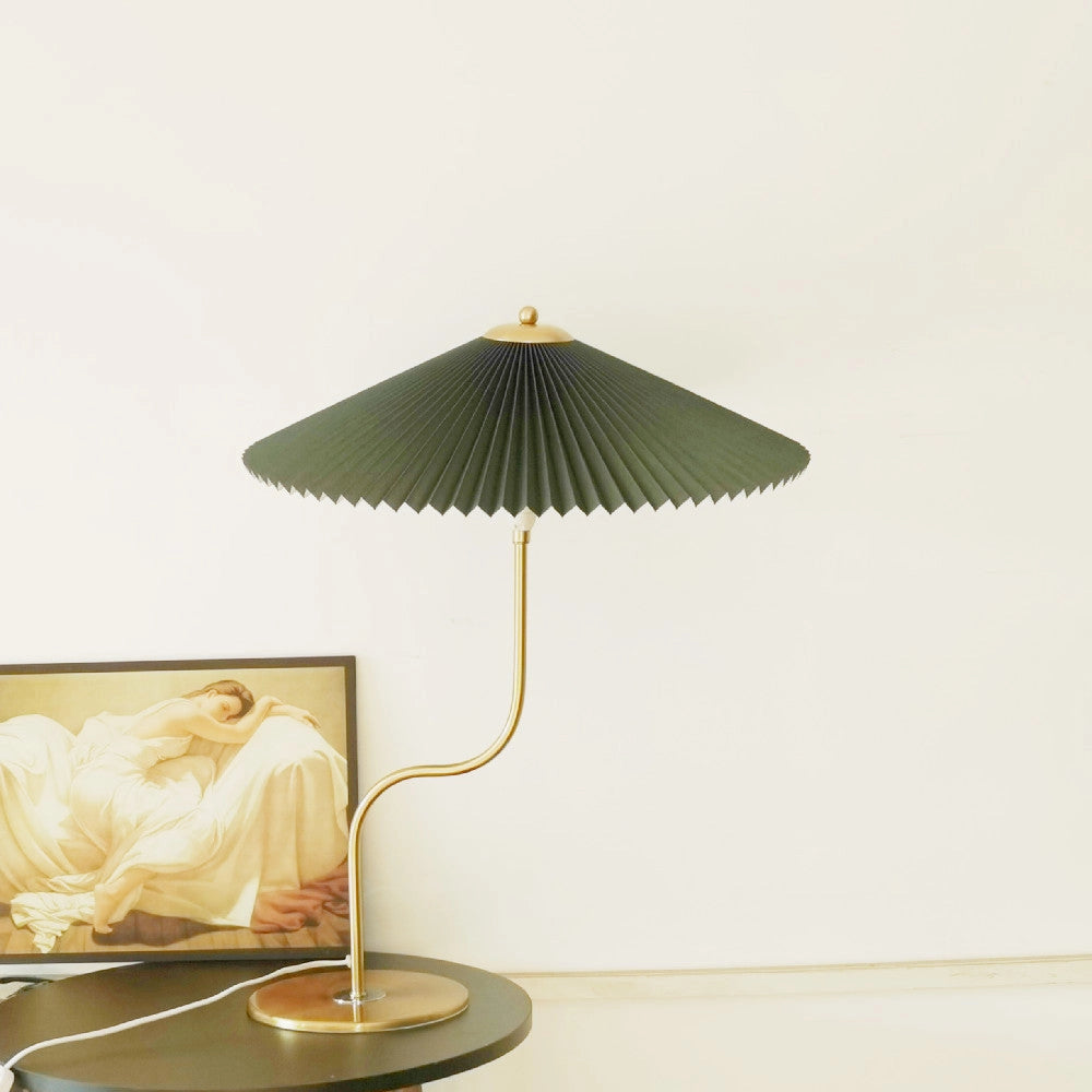 Dark green table lamp with an umbrella-shaped shade featuring yellow diamond, khaki, and white flower patterns, placed on a wooden table.