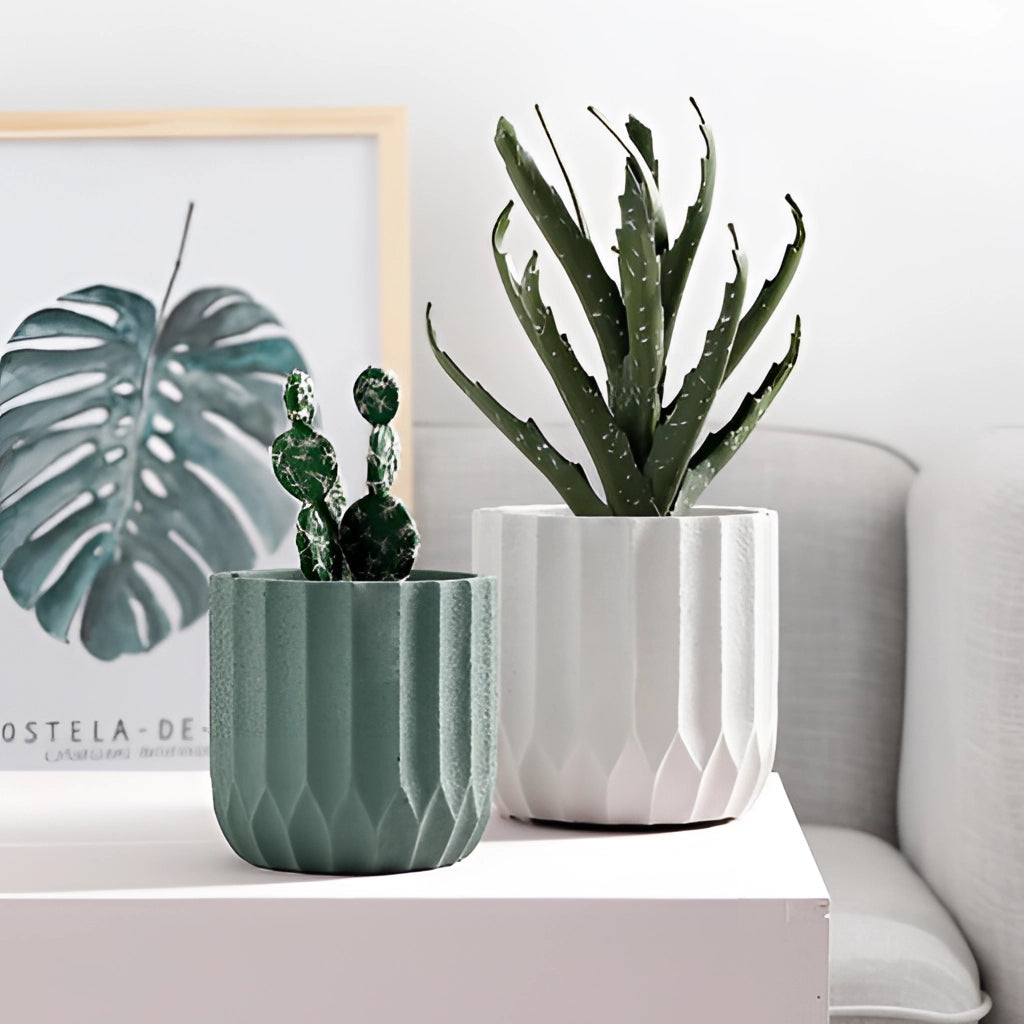 Textured ceramic polygon vase with a geometric design, holding a lush green houseplant, placed on a table near a comfortable couch.