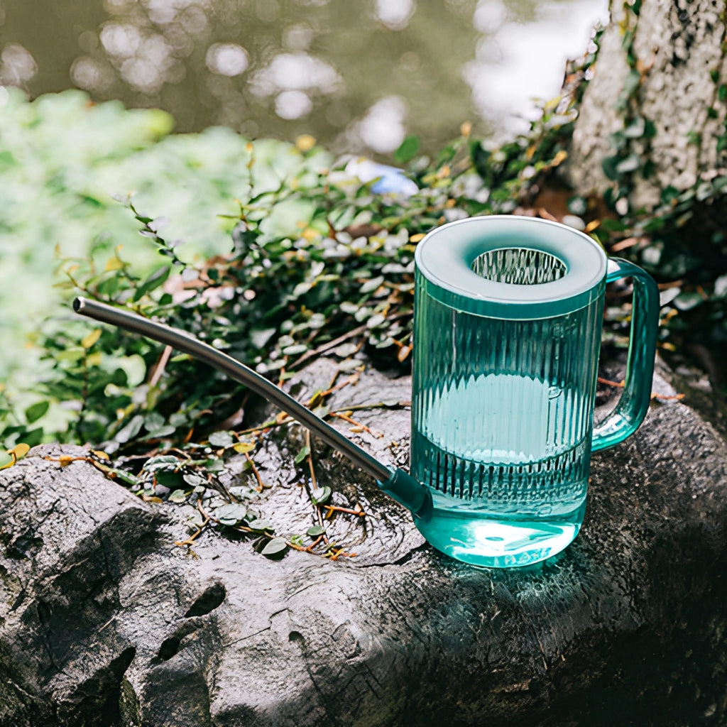 A blue watering can with an extended spout, designed for precise water delivery, placed on green grass.