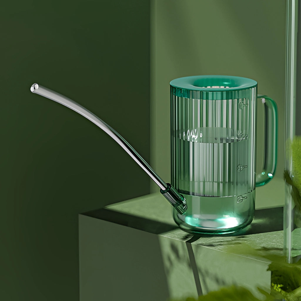 A transparent watering can with an extended spout designed for accurate water delivery, made from glass and metal.