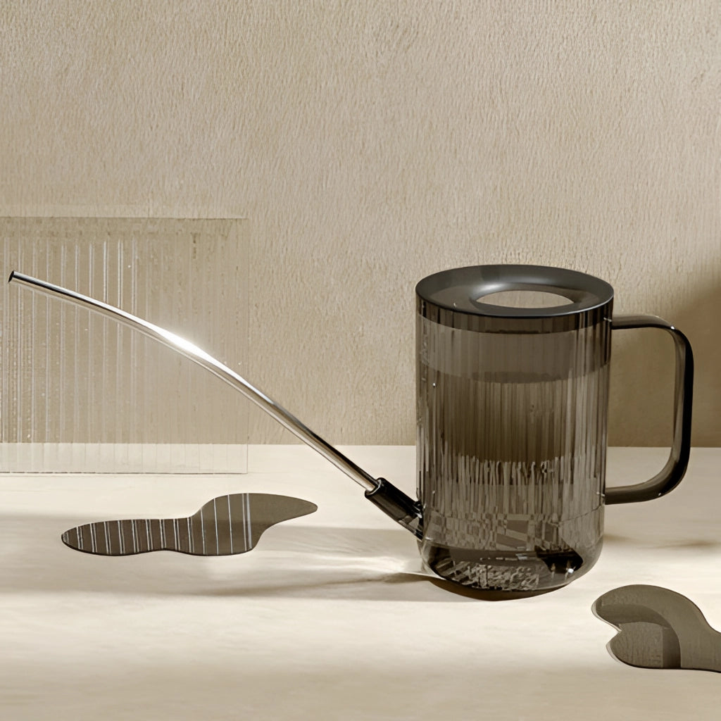 A watering can with an extended spout placed on a wooden table.