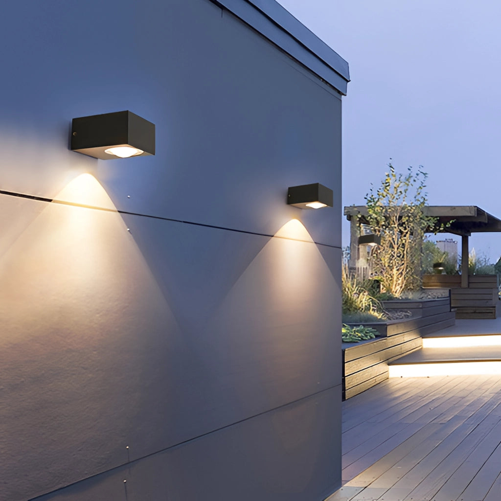 A sleek, black, UFO-shaped waterproof wall light mounted on an urban building facade during the daytime.