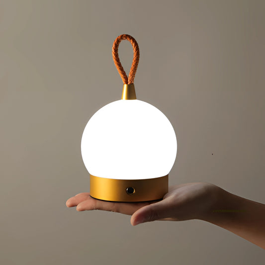 Waterproof LED lamp blimp on a wooden nightstand, emitting an amber glow, with a cordless design and quick charging feature.