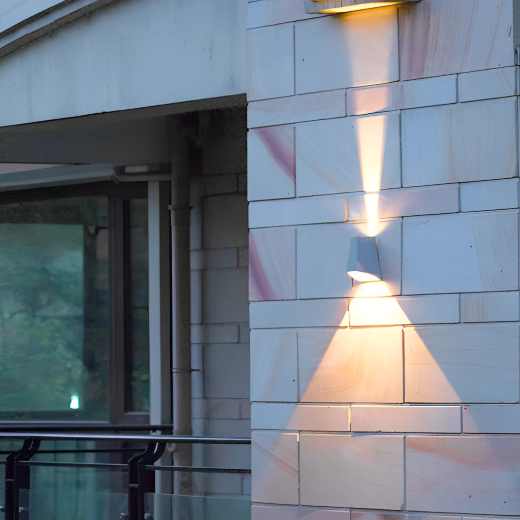 A modern waterproof pyramid-shaped LED wall sconce mounted on an exterior wooden wall, providing ambient lighting to a building facade.