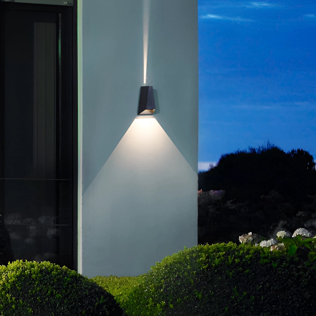 Waterproof Outdoor Pyramid LED Wall Sconce mounted on an exterior wall with a background of greenery, including trees and plants, under a clear blue sky.
