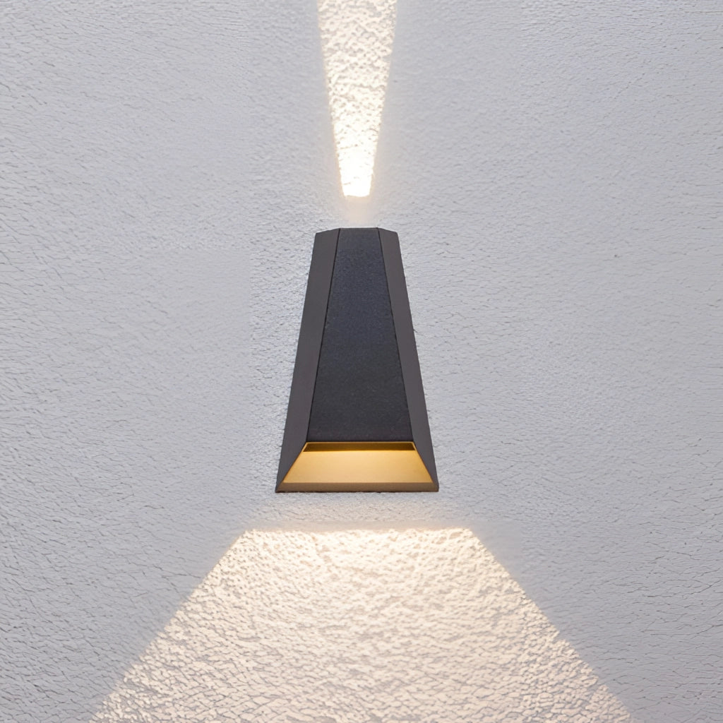 Waterproof Outdoor Pyramid LED Wall Sconce in Black emitting Warm White light, mounted on a wooden wall.